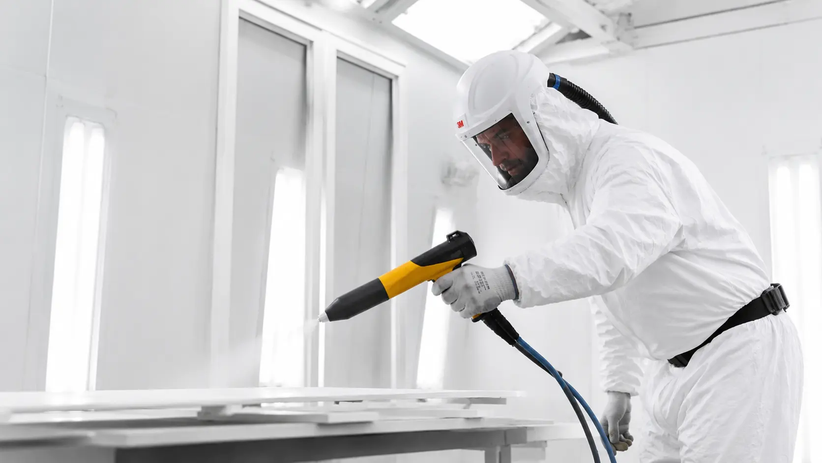 Worker applying coating in a paint booth